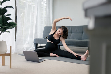 Fototapeta na wymiar Beautiful pregnant asian woman is stretching her body in front of her laptop for the online yoga practicing to keep her prenatal healthy. Concept healthy pregnancy. 