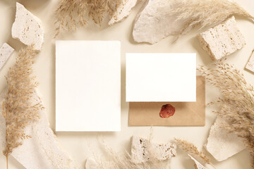 Blank cards near beige travertine stones and dried pampas grass top view, greeting mockup