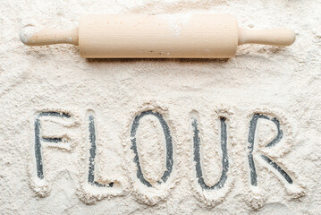 Background with flour and rolling pin, top view.