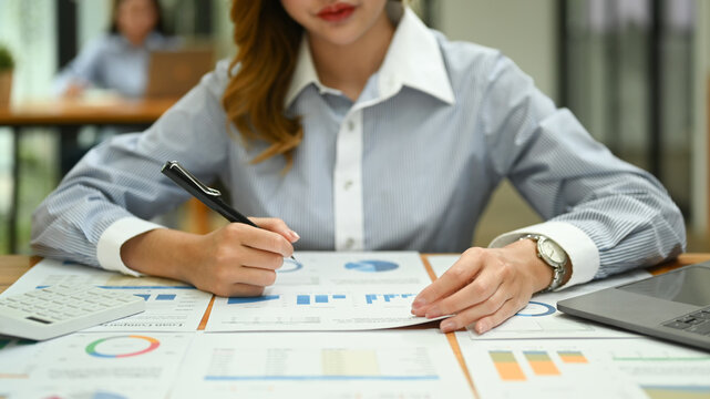 Young female economist analyzing statistics , commerce data, marketing plan at her office desk
