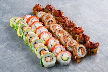 set of different colorful maki sushi rolls with tuna, salmon, shrimp, crab and avocado on a dark gray background