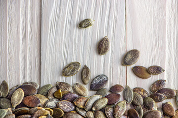 Pumpkin seeds on a white wooden background.