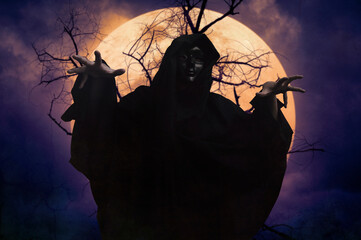 Grim reaper standing over dead tree, full moon and spooky cloudy sky, Halloween mystery concept