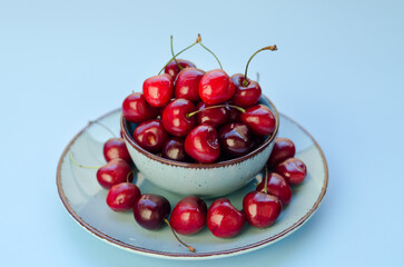 Top view of red sweet cherry on blue plate close up. Vegan, summer food concept. Diet