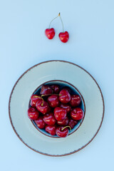 Top view of red sweet cherry on blue plate close up. Vegan, summer food concept. Diet