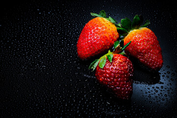 Red strawberries with green leafs, isolated on black background, close-up. Selective Focus.