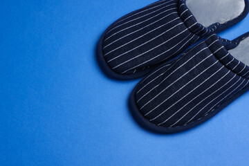 Pair of stylish slippers on blue background, space for text
