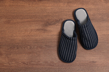 Pair of stylish slippers on wooden floor, top view. Space for text