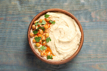 Bowl of tasty hummus with chickpeas and parsley on wooden table, top view
