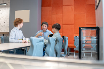 Schoolteacher having a conversation with his pupils at lunch