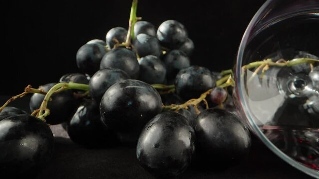 grapes and a glass of wine overturned on the table, the camera drives into it. Dolly slider extreme close-up.