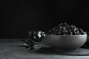 Fototapeta na wymiar Bowl of delicious ripe black mulberries on grey table, space for text