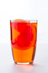 Grapefruit herbal tea with ginger and honey in a glass cup on white background