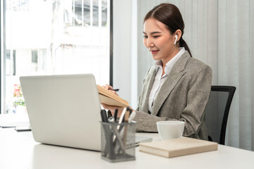 Asian businesswoman taking notes in a notebook, Note the main content and details of the main points of the document, Analyzing statistical graph data to improve or develop the organization to grow