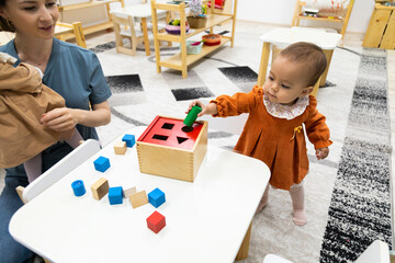 Toddler playing with montessori Imbucare shapes box