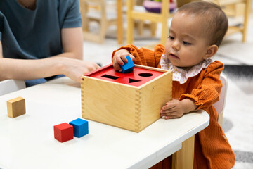 Toddler playing with montessori Imbucare shapes box - obrazy, fototapety, plakaty