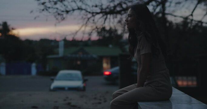 Cinemagraph of loneliness woman sitting against the evening road background