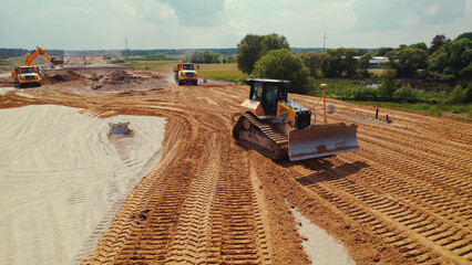 Active work on a road building site. A dumper truck with earth in a body, transporting it. Heavy construction machinery. Warsaw, Poland. Top aerial view. High quality photo
