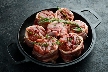 Raw meat medallions wrapped in bacon. in a pan, ready to cook. On a concrete background. Side view.