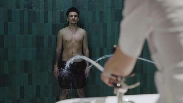 Close up man have anti-cellulite treatment experiencing douche. Hands of nurse regulate Charcot douche equipment at spa center. Water massage. Slow motion