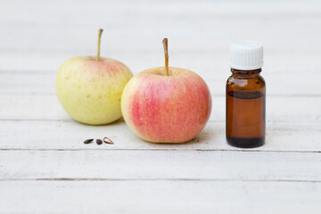 apple seed, apple kernel esssential oil bottle with apples on wooden and greenery background