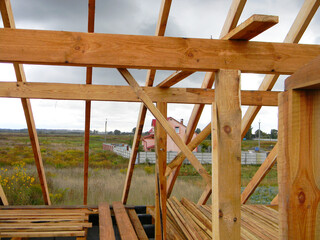 Wood framing during the roofing construction.Timber trusses, roof framing with a close-up of roof beams, struts and rafters against a cloudy rainy weather.