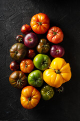 Different colors tomatoes mix on black background