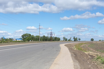 Fototapeta premium Electric tower and metal water tank standing high above trees on sunny day. Clouds and blue sky in background. Copyspace available, no people