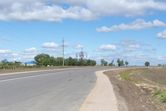 Electric tower and metal water tank standing high above trees on sunny day. Clouds and blue sky in background. Copyspace available, no people