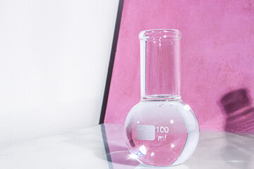 Transparent glass flask on a pink background. science research chemistry banner laboratory background.