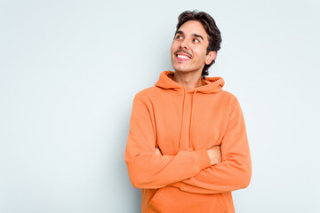 Young hispanic man isolated on blue background smiling confident with crossed arms.