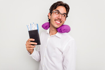 Young hispanic man with inflatable travel pillow holding passport isolated on white background looks aside smiling, cheerful and pleasant.