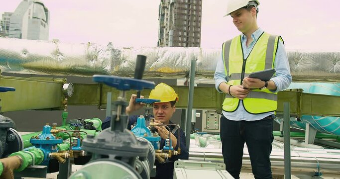 Portrait Professional Inspector Engineer foreman in hardhat working checking the valve pipelines and recheck system data spec on rooftop of construction site