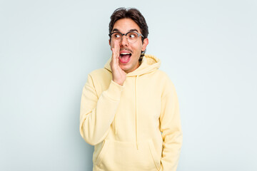 Young hispanic man isolated on blue background shouting excited to front.