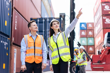Caucasian business man and woman worker working in container terminal.