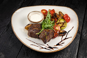 grilled meat with vegetables and spices on a black background
