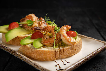 Bruschetta with seafood and greens on a white plate.
