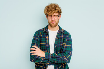 Young caucasian man isolated on blue background unhappy looking in camera with sarcastic expression.
