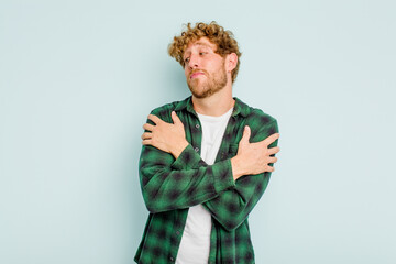 Young caucasian man isolated on blue background hugs, smiling carefree and happy.