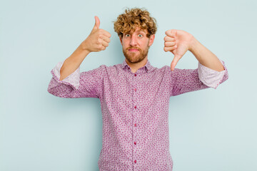 Young caucasian man isolated on blue background showing thumbs up and thumbs down, difficult choose...