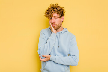 Young caucasian man isolated on yellow background who is bored, fatigued and need a relax day.
