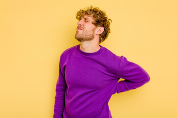 Young caucasian man isolated on yellow background suffering a back pain.