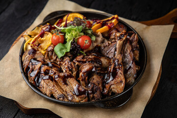 grilled meat with vegetables and spices on a black background
