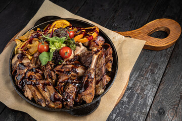 grilled meat with vegetables and spices on a black background
