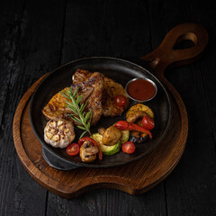 grilled meat with vegetables and spices on a black background
