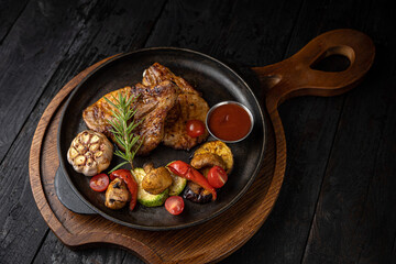 grilled meat with vegetables and spices on a black background

