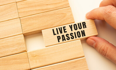 Hand holds a wooden cube with the text LIVE YOUR PASSION.