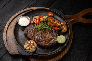grilled meat with vegetables and spices on a black background
