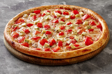 Pizza with mozzarella, tomatoes, blue cheese and dried basil on wooden serving board