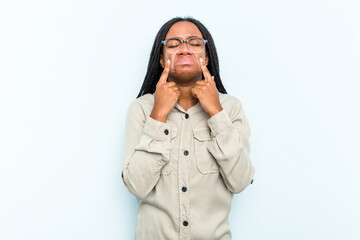 Young African American woman with braids hair isolated on blue background crying, unhappy with something, agony and confusion concept.